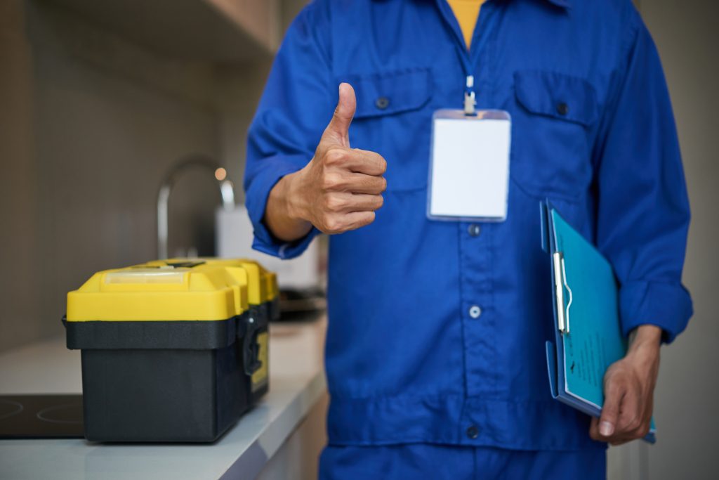 unrecognizable male plumber standing near kitchen sink showing thumb up